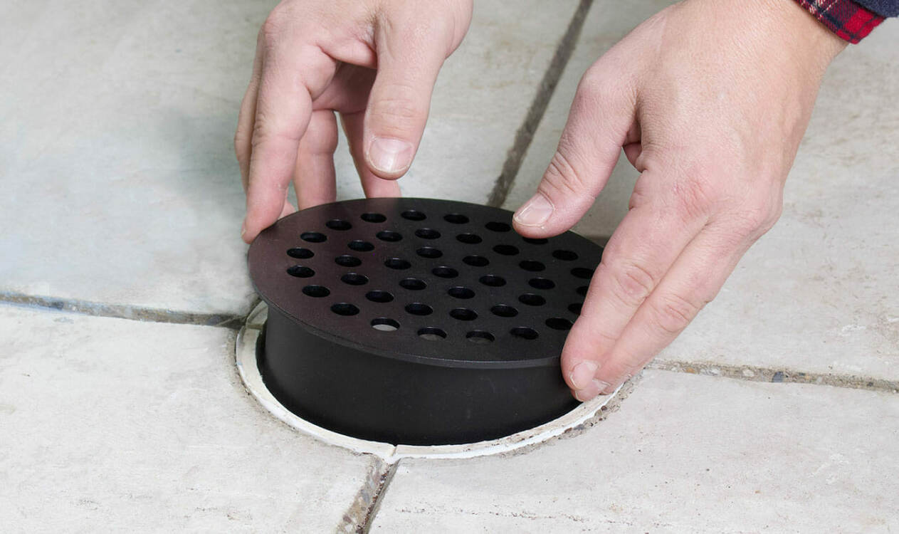 Someone installing a new garage floor drain cover