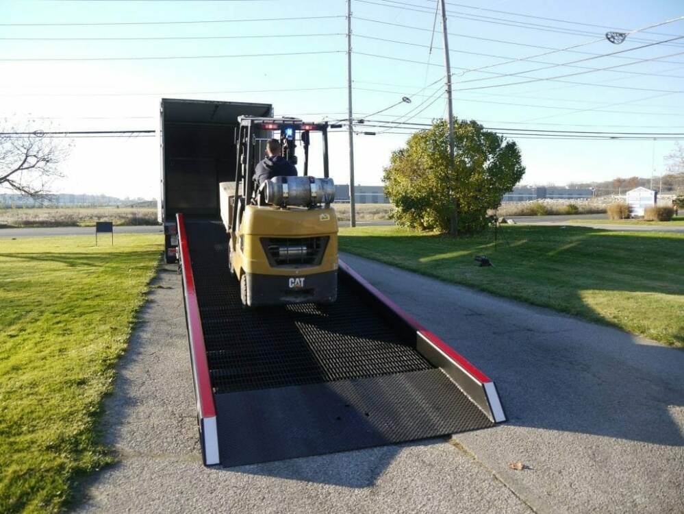 Forklift traveling up yard ramp towards truck trailer